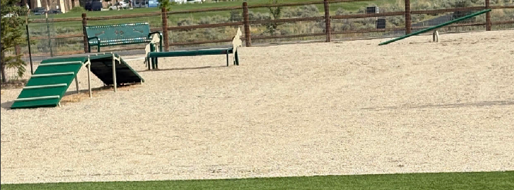 Green dog park A-frame, paws table, seesaw, and bench installed in a Summit County, Utah dog park