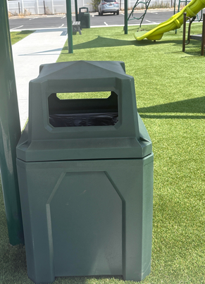 Green recycled-plastic litter receptacle with pyramidal lid at a Kamas City, Utah playground