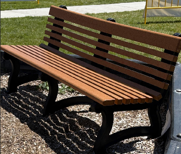 Brown and black recycled-plastic park bench installed on wood-chip mulch in Summit County, Utah