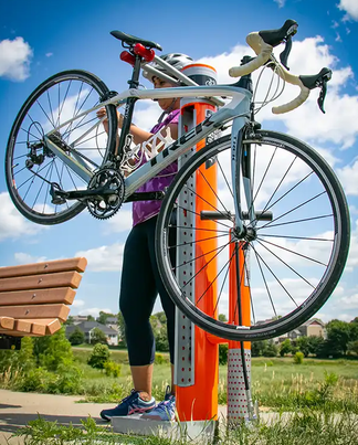 Bike Repair Stations — cyclist using a Dero Fixit public bike repair station beside a park path
